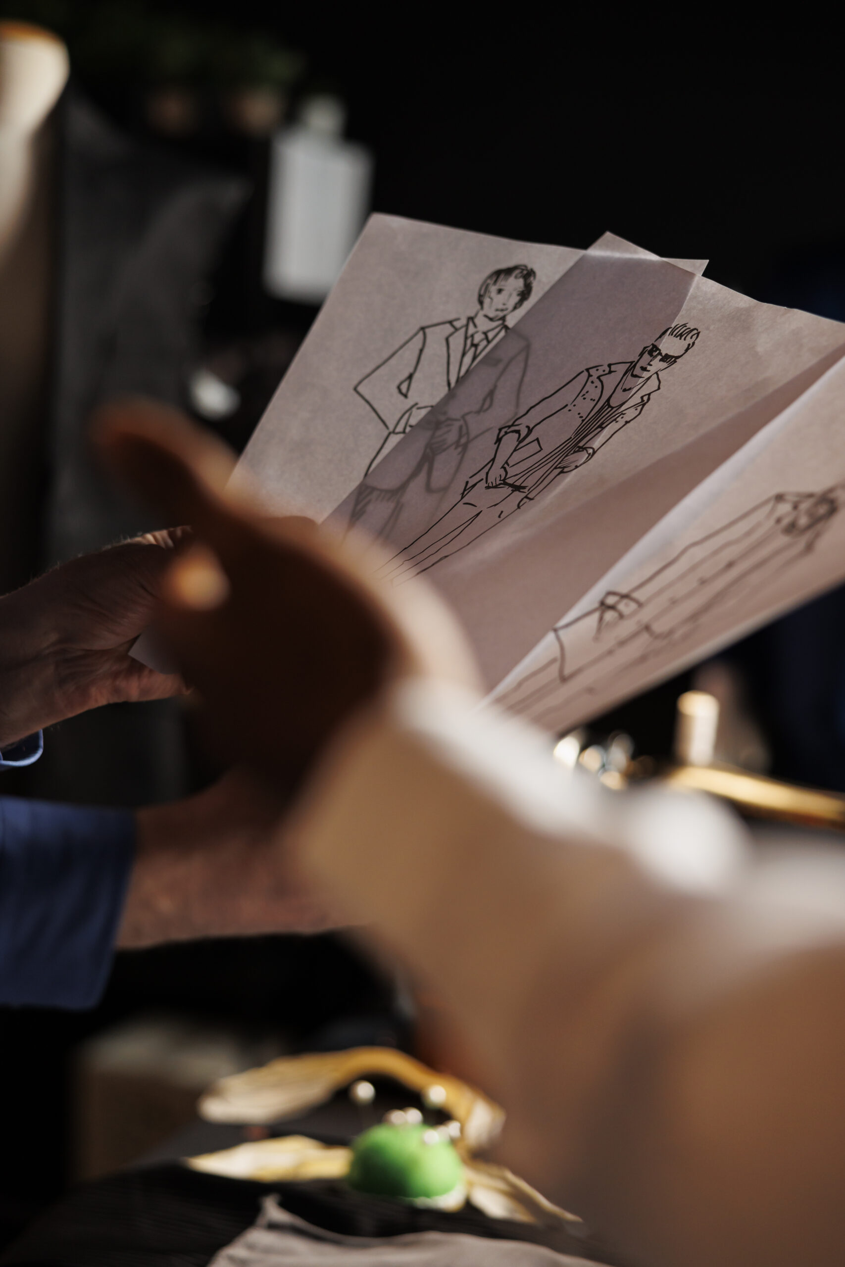 Close up of technical sketch representations of stylish bespoke sartorial pieces in atelier shop studio. Experienced couturiers coming up with ideas for upcoming luxury clothing collection